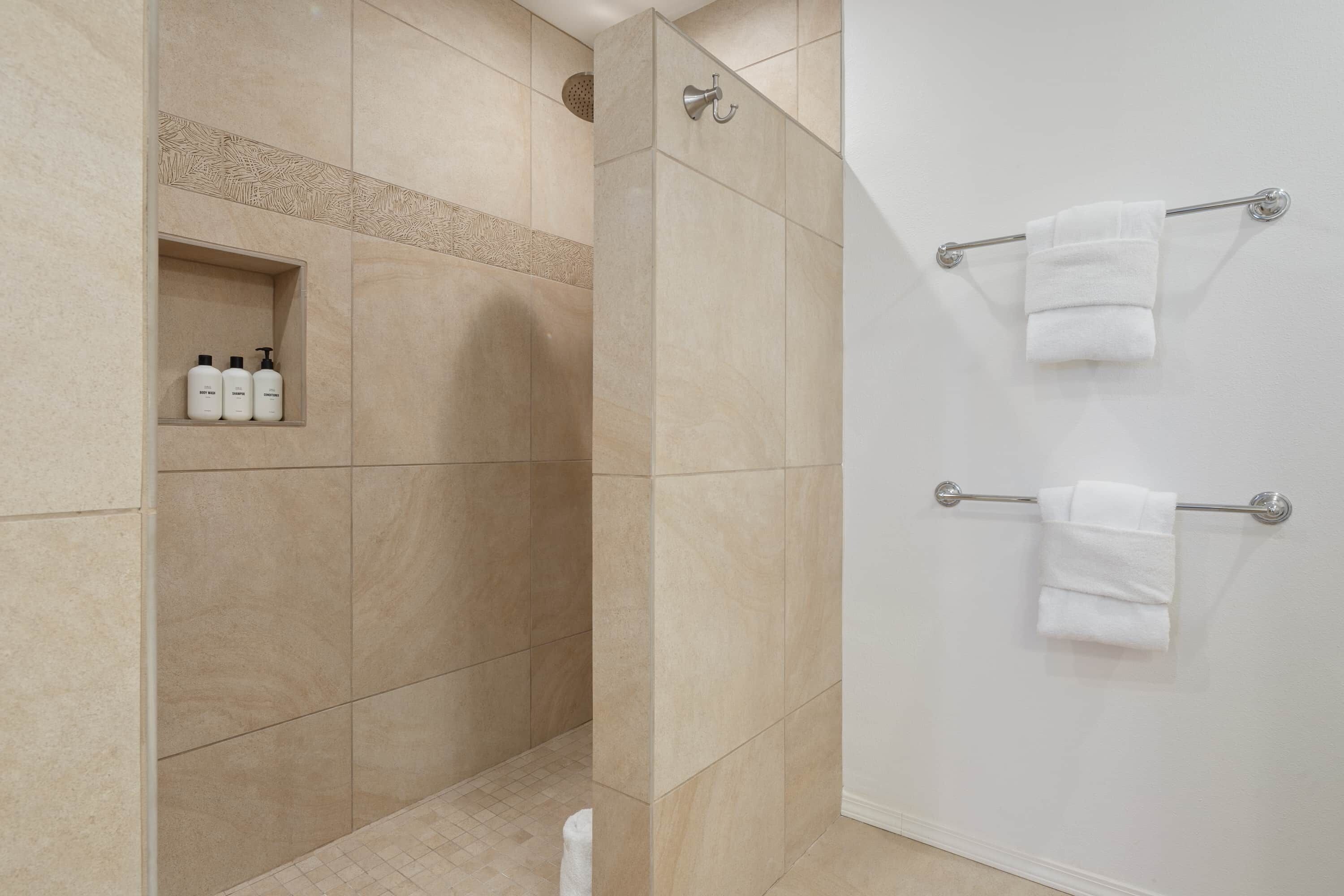 Un baño moderno con ducha, paredes de azulejos y un perchero.