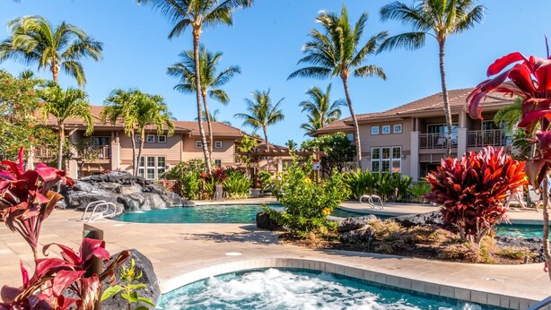 Un resort con diverse piscine, palme e un edificio con balconi.