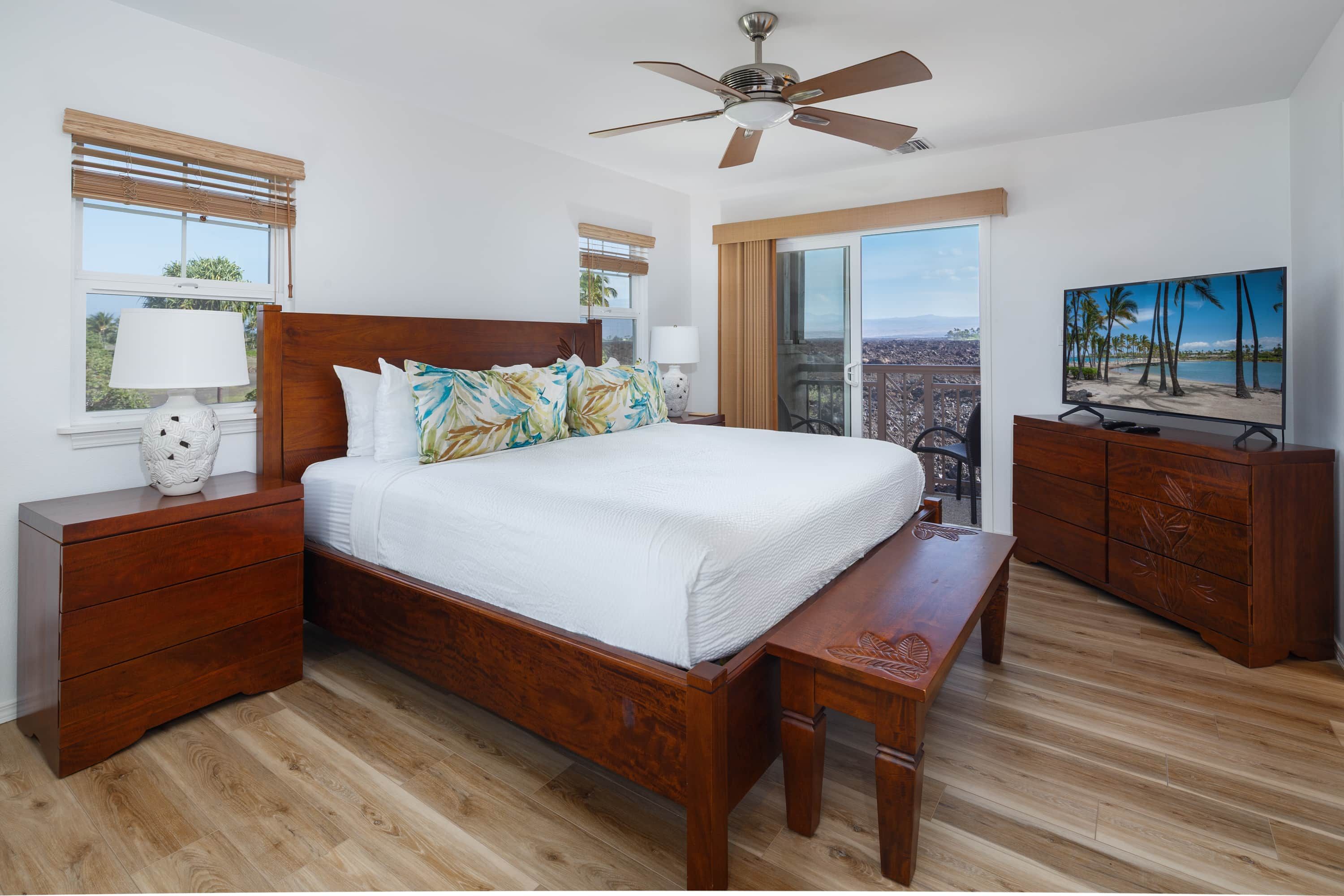A hotel bedroom with a bed, bedside tables, a bench, a TV, and a balcony with a view.