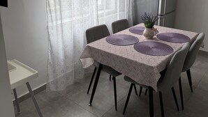 A dining area with a table set for four, a refrigerator, and a window with sheer curtains. - Modern family home near Debrecen Airport &City Center, with own bathroom&kitchen (Debrecen)
