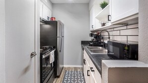 A compact kitchen with a refrigerator, stove, microwave, and sink. - Arlington 1BR | AT&T, Globe Life, 6 Flags, Parking (Arlington)