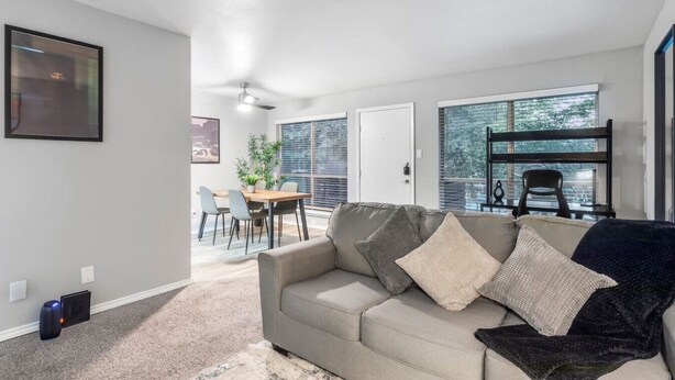 A living room with a sofa, a dining table with chairs, a ceiling fan, and a view through a window. - Arlington 1BR | AT&T, Globe Life, 6 Flags, Parking (Arlington)