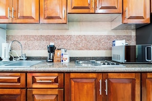 Eine Küche mit Holdelementen, einer gefliesten Spritzschutzwand, einer Spüle, einer Kaffeemaschine, einer Mikrowelle und einem Gasherd.
