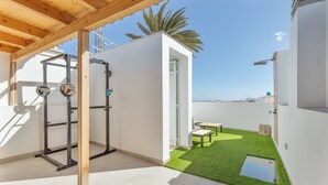 A modern outdoor gym area with a weightlifting station and a small seating area with a table and chairs. - House with Private Terrace Near the Sea and Wi-Fi in Gran Canaria (Telde)
