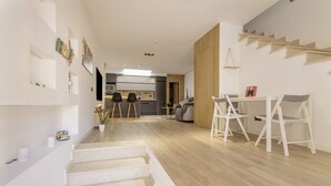 A modern interior with a staircase, a dining area with white chairs, and a kitchen in the background. - House with Private Terrace Near the Sea and Wi-Fi in Gran Canaria (Telde)