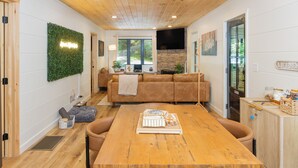 Un intérieur moderne avec un plafond en bois, un canapé, une table à manger et une cheminée en pierre.