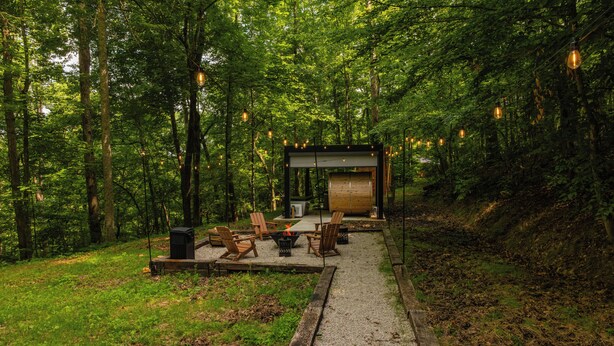 Un espace boisé doté d’une structure en bois, de sièges en plein air et de guirlandes lumineuses.