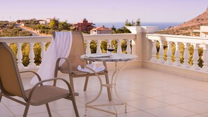 A balcony with two chairs and a table, overlooking a coastal landscape with buildings and hills. - villa Kokalis resort 4 with private pool with a fantastic view (Γουβες)