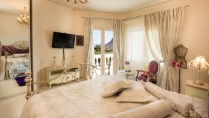 A bedroom with a large bed, a television, a dresser, a chair, and a view of the outdoors. - villa Kokalis resort 4 with private pool with a fantastic view (Γουβες)