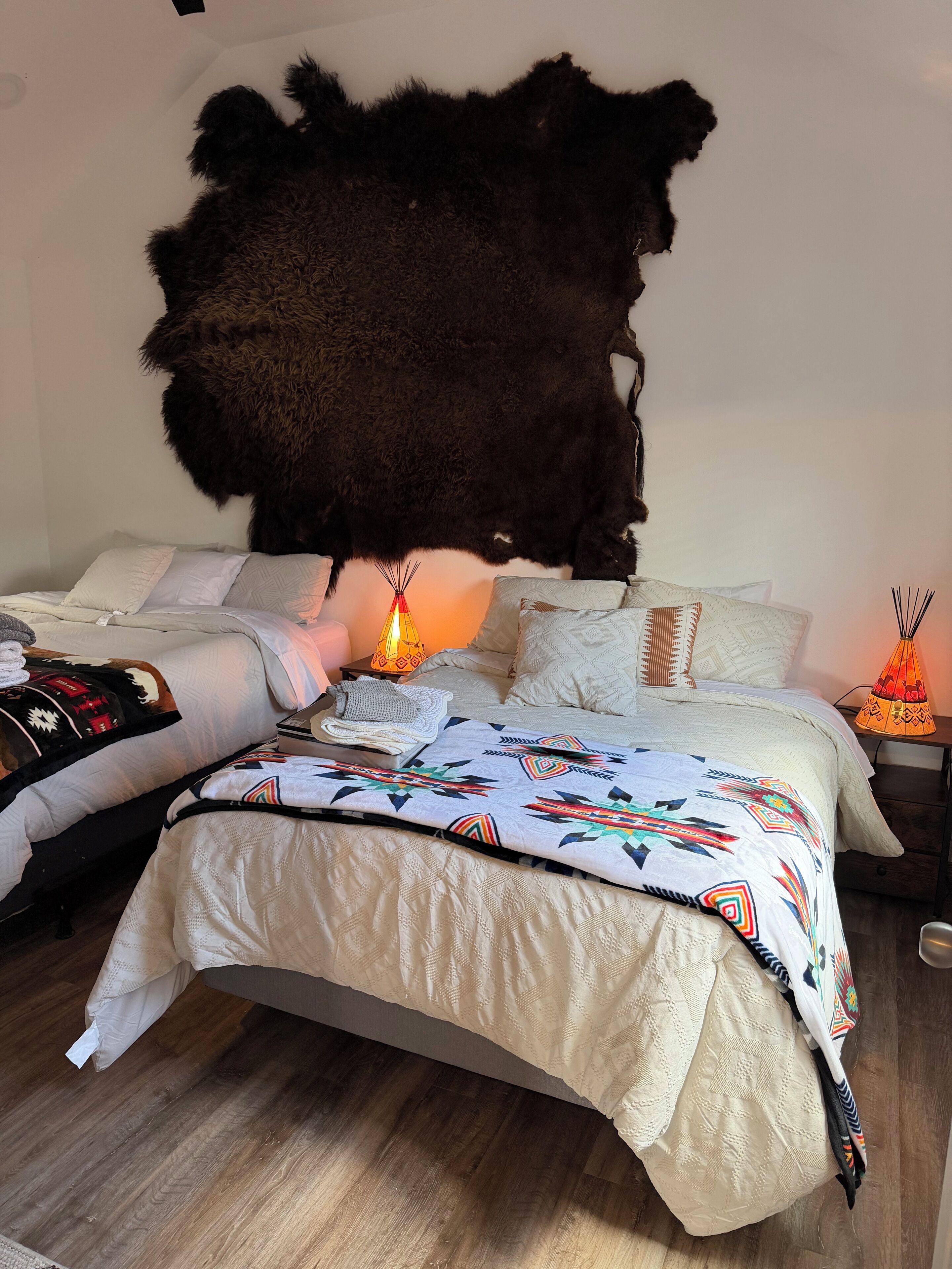 Un dormitorio con un amplio felpudo de piel, una colcha estampada y una pequeña lámpara en una mesita de noche.