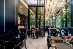 An indoor dining area with tables and chairs, large windows, and a modern interior design. - High Tree Resort, Krabi (Krabi)