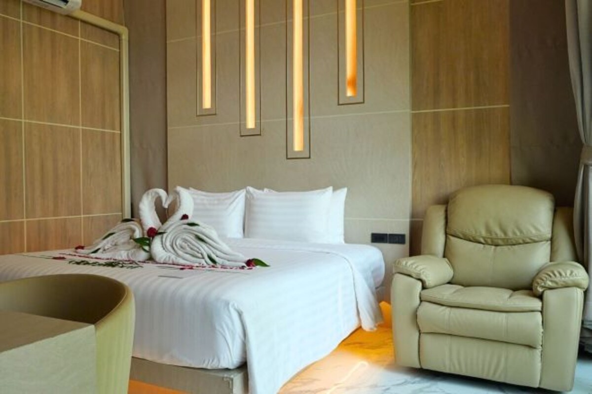 A hotel room with a bed, a chair, and a wall with vertical light fixtures.