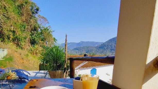Una mesa con una taza de café, un vaso de jugo y un plato de comida, con vistas a un paisaje montañoso.