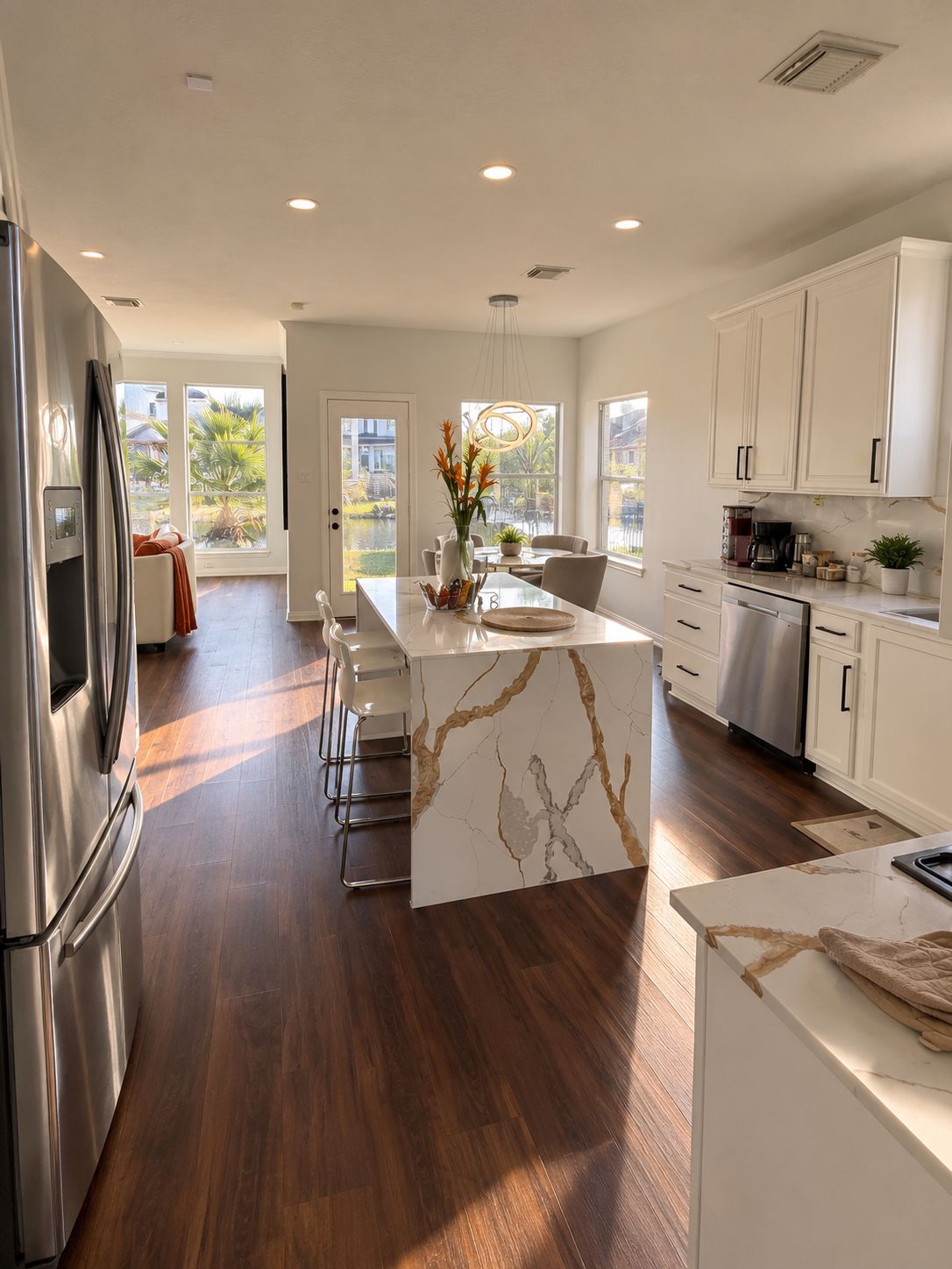 A modern kitchen with a marble island, stainless steel appliances, and a view of a pool.