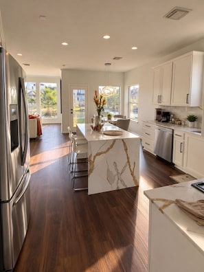 A modern kitchen with a marble island, stainless steel appliances, and a view of a pool. - Luxury Lake Front +Private Dock +Kayak +Fishing +4BR, 3.5Bath +Sleeps 12 (Cypress)