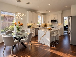 A modern kitchen with white cabinets, a marble island, and stainless steel appliances. - Luxury Lake Front +Private Dock +Kayak +Fishing +4BR, 3.5Bath +Sleeps 12 (Cypress)