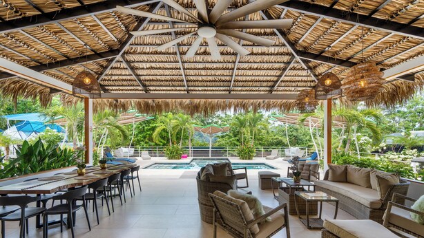An outdoor lounge area with a pool, thatched roof, and wicker furniture. - King Suite w Pool + Game Room + 5 min. to the Beach (Potrero)