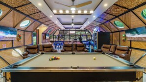 A pool table with leather chairs, a ceiling fan, and a large window with a view of the outdoors. - King Suite w Pool + Game Room + 5 min. to the Beach (Potrero)