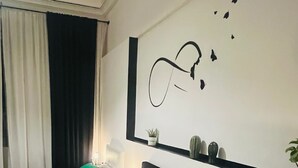 Una camera d'albergo moderna con un letto grande, cuscini verdi, un comodino con una lampada e un quadro appeso sopra il letto.