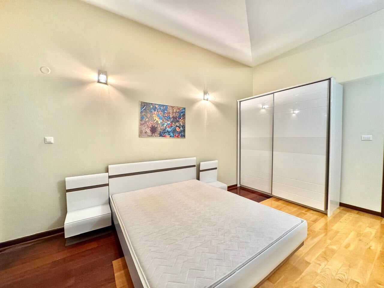 Ein Schlafzimmer mit einem Bett, einem Kleiderschrank und zwei Wandleuchten.