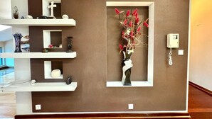 A modern interior with a brown accent wall, white shelves, and a decorative vase with red flowers. - Rooftop Elegance Suite (Budva)