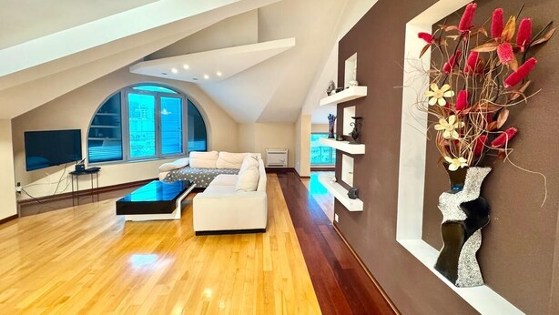 A spacious living room with a high ceiling, a white sofa, a coffee table, and a large window. - Rooftop Elegance Suite (Budva)