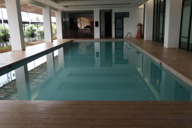 An indoor swimming pool with clear water, surrounded by a wooden deck and white walls.