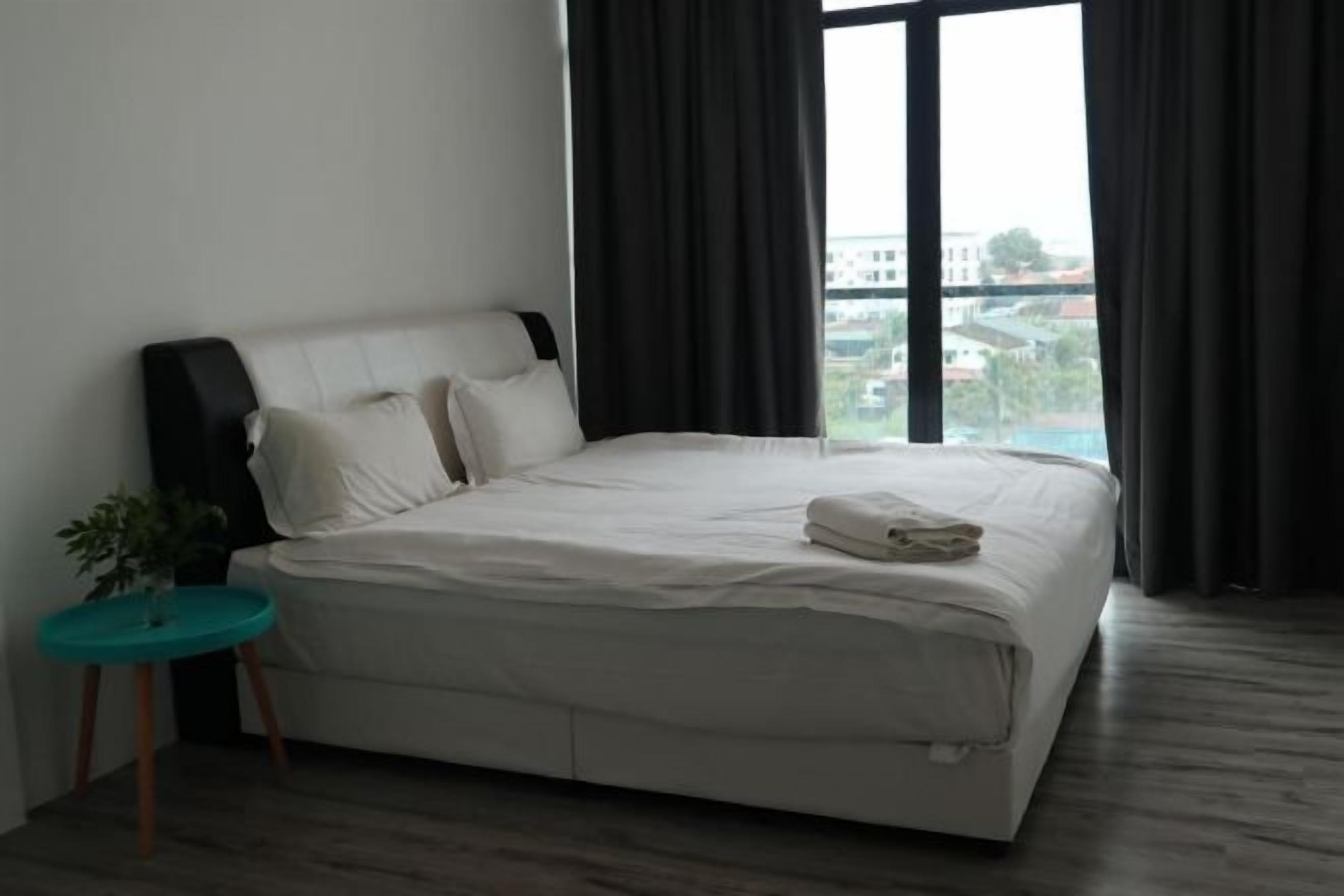 Et moderne hotelværelse med en stor seng, et lille sengebord og udsigt til bybilledet gennem vinduet.