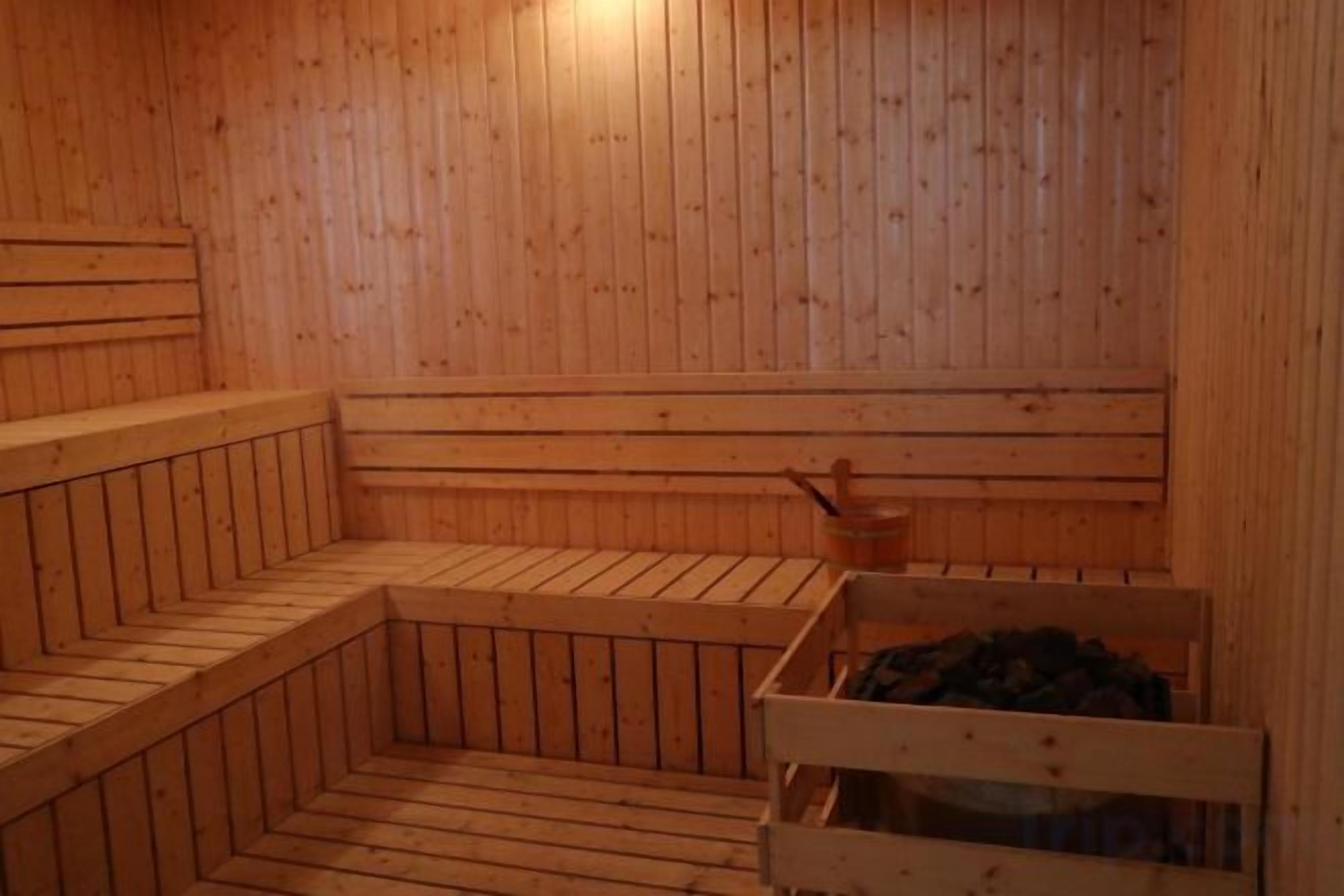 Sauna, jossa on puiset lauteet ja yksi lauteista on varustettu korilla, jossa on erilaisia tavaroita.
