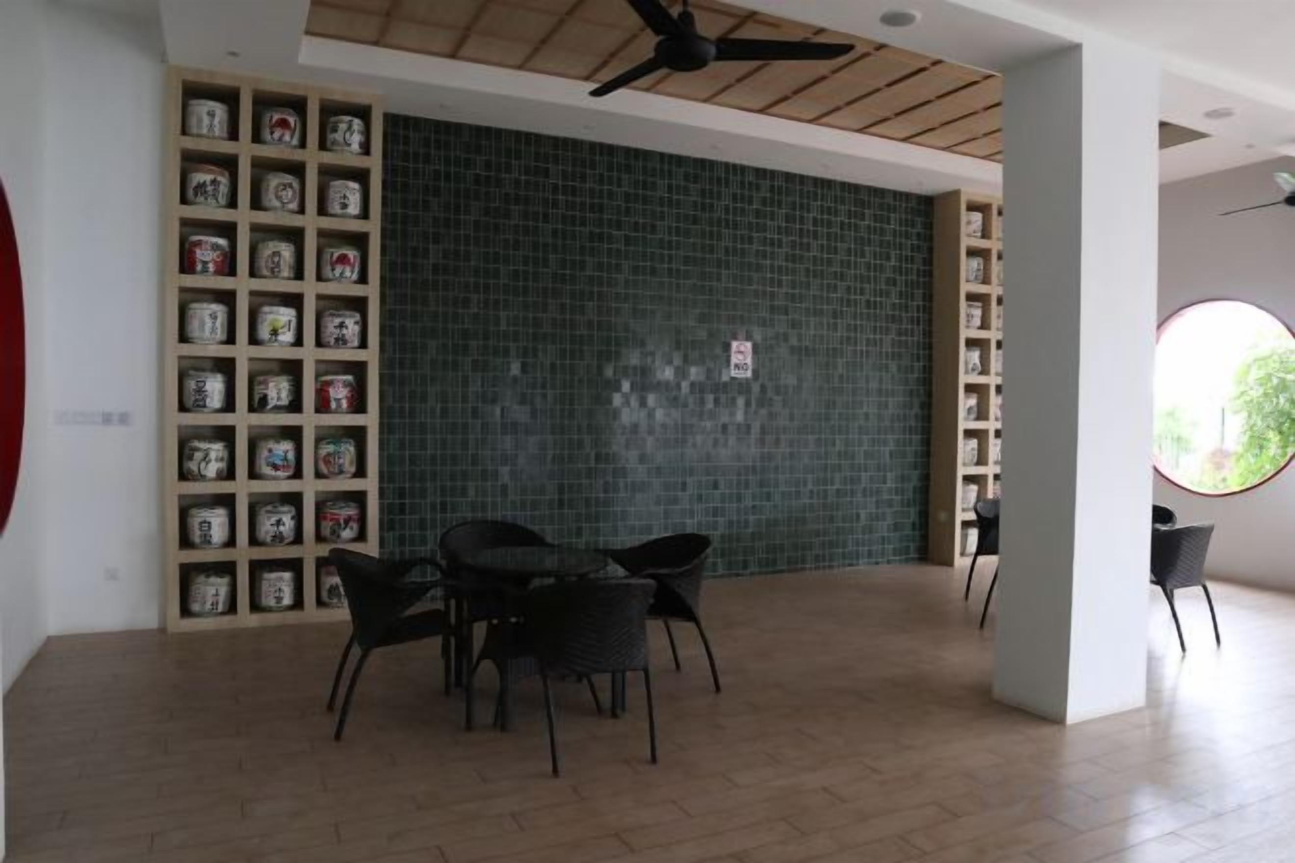 A room with a tiled wall, a ceiling fan, a bookshelf, and a round window.