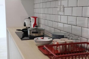 A kitchen with a stove, a kettle, and a red tray. - Zen66 @ Roxy Serviced Apartment (Kuching)