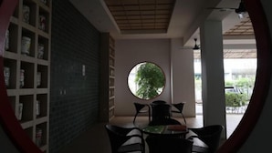 A room with a round window, a table with chairs, and a shelving unit with items. - Zen66 @ Roxy Serviced Apartment (Kuching)
