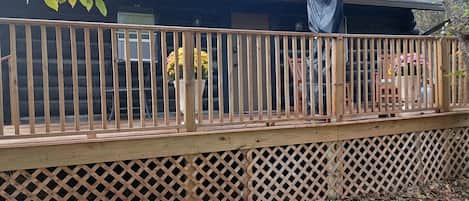 A wooden deck with a lattice fence, a covered area, and a house in the background.