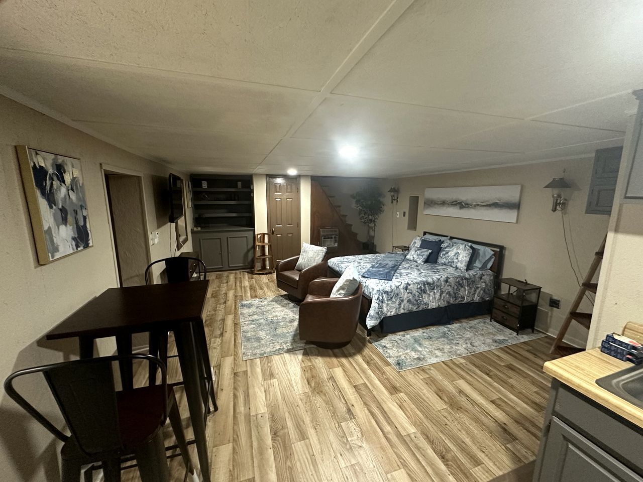 A bedroom with a bed, a desk, a chair, and a staircase leading to an upper level.