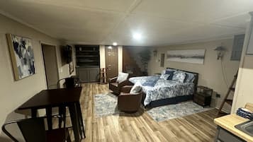 A bedroom with a bed, a desk, a chair, and a staircase leading to an upper level.