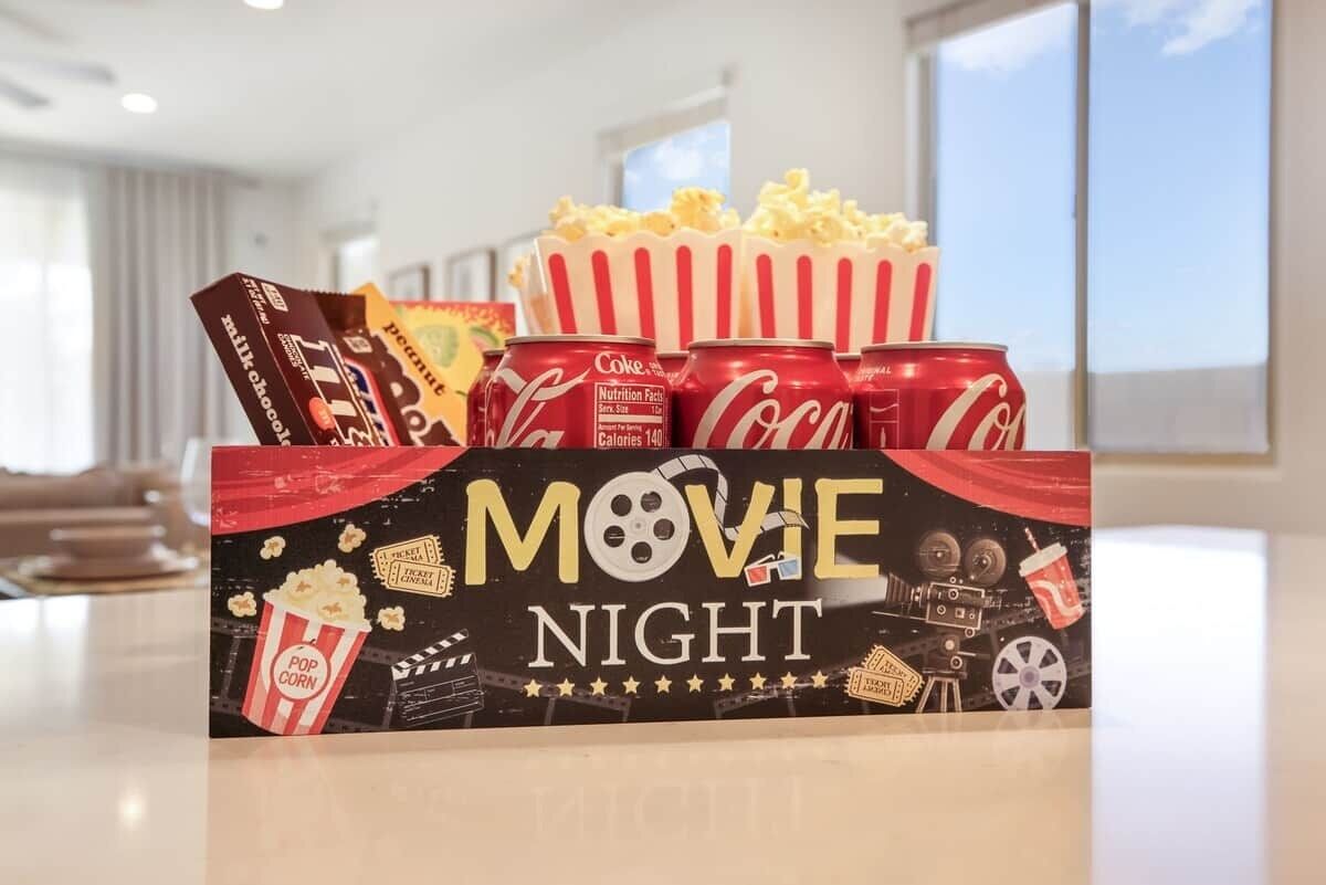 Een opstelling voor een filmavond met popcorn, chocoladerepen en blikjes Coca-Cola.