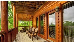 A wooden porch with a covered roof, wooden chairs, and a table. - Bearly Chocolate (Sevierville)