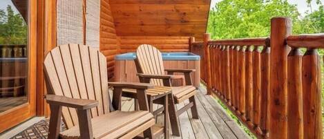 A wooden deck with Adirondack chairs and a hot tub.