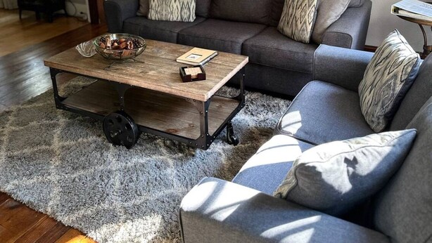 Un salon chaleureux avec un canapé gris, une table basse en bois et un tapis moelleux.