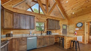 A spacious kitchen with wooden cabinets, a granite countertop, and a built-in dishwasher. - Majestic View (Sevierville)