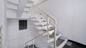 A modern staircase with white steps and wooden handrails. - Capital O 94914 Kemayoran Guest House (Jakarta)