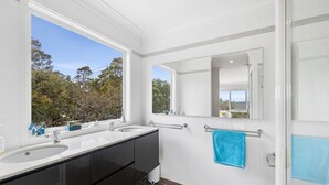 A modern bathroom with two sinks, a large mirror, and a view of trees outside. - Rally House Fairhaven (Fairhaven)