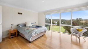 A bedroom with a large window, a bed, a bedside table, and a chair. - Rally House Fairhaven (Fairhaven)