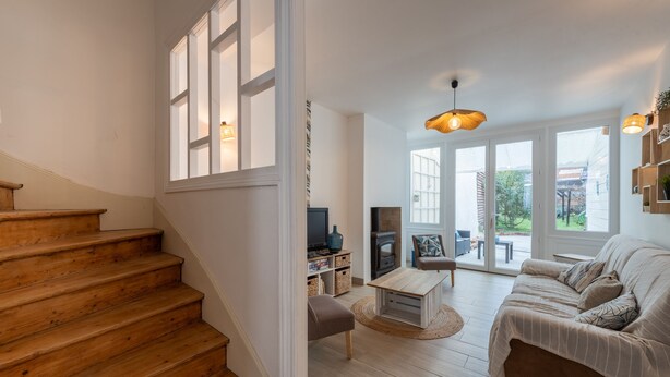 Amplia sala de estar con una escalera de madera, un sofá, una mesa de centro y una chimenea.
