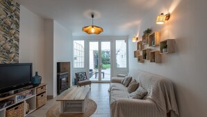 Una sala moderna con un sofá, televisión y estanterías de madera.