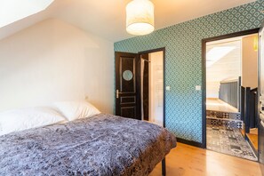 Ein Schlafzimmer mit einem Bett, einer Tür zu einer Treppe und strukturierter Tapete.