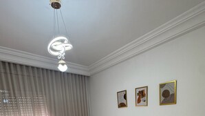 Et soveværelse med en stor seng, et natbord, en bænk og en loftslampe.