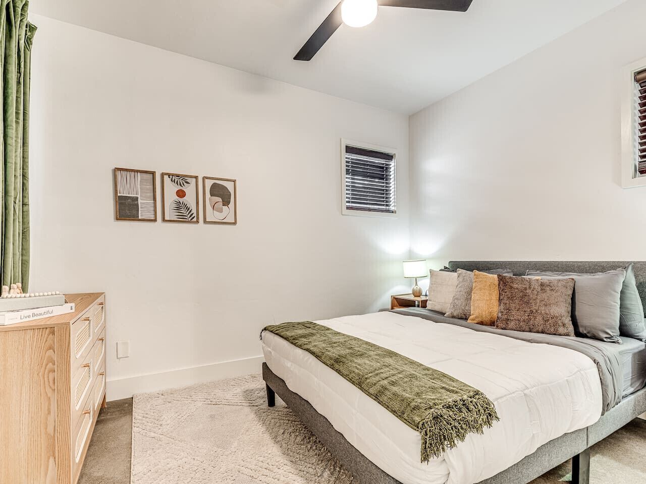 Ein Schlafzimmer mit einem Bett, einem Nachttisch, einer Lampe und einem Kunstwerk an der Wand.