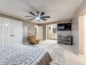 A bedroom with a bed, a chair, a ceiling fan, a TV, and a dresser. - Ranchwood Manor Escape: Pool, Yard, Comfort in OKC (Oklahoma City)