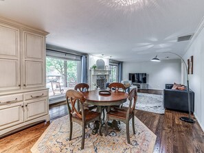 A dining area with a round table and chairs, a large cabinet, and a fireplace. - Ranchwood Manor Escape: Pool, Yard, Comfort in OKC (Oklahoma City)